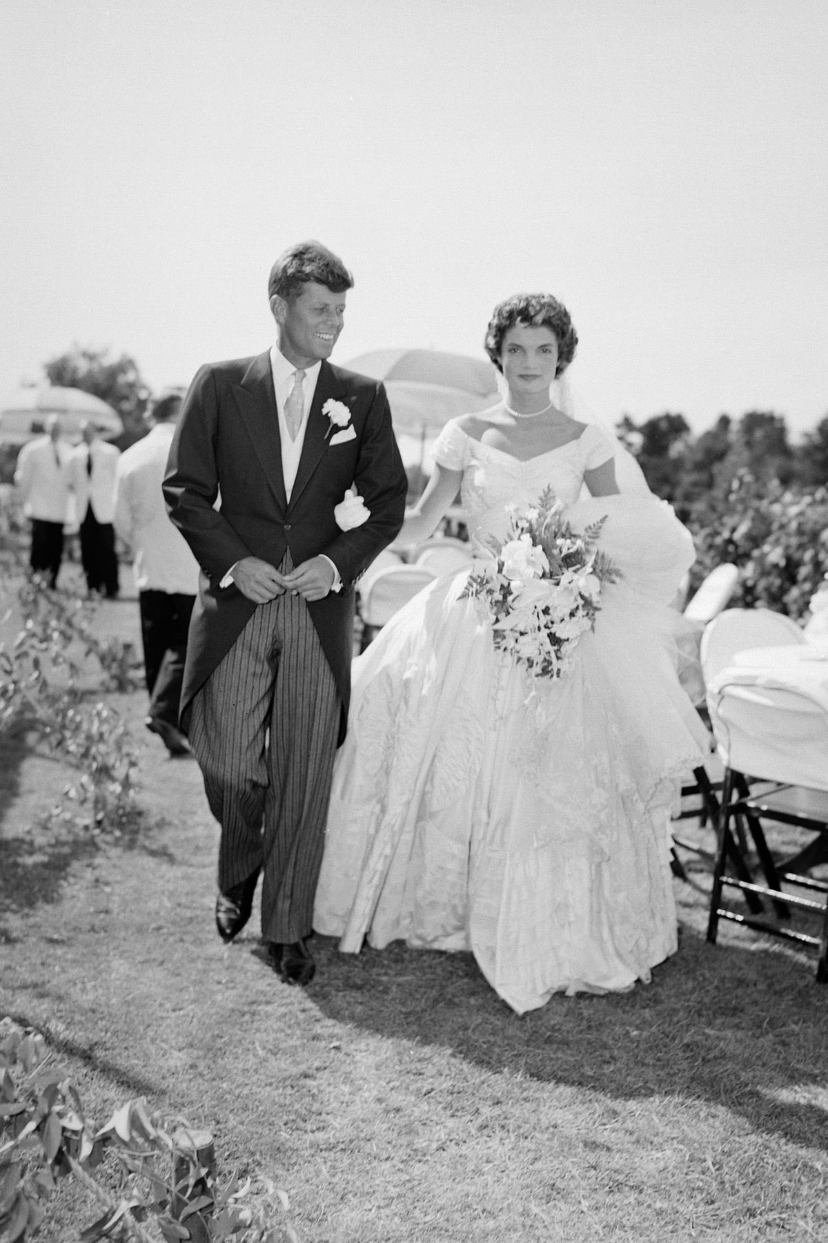 una scena dello sposo kennedy bouvier john cammina accanto alla sua sposa jacqueline a un ricevimento all